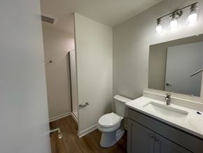 Belgium apartment for rent - A bathroom with a toilet, sink, and mirror.