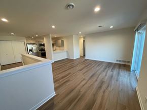 Belgium apartment for rent - A spacious room with wooden flooring and white walls.