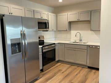 Belgium apartment for rent - A kitchen with a stainless steel refrigerator and wooden floors.