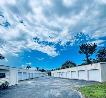 Daytona Beach apartment for rent - A long row of white garage doors under a blue sky with clouds.
