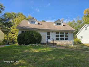 Hazelwood house for rent - the front of a white house with a lawn and trees