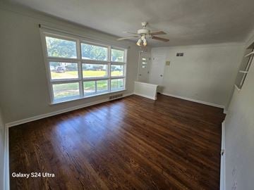 Hazelwood house for rent - a living room with wood floors and a large window and a ceiling fan