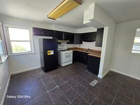 Hazelwood house for rent - an empty kitchen with black cabinets and white appliances