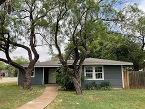 Abilene house for rent - A house with a grey roof and a tree in front of it.