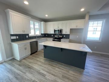 Wilson house for rent - a kitchen with white cabinets and a large island