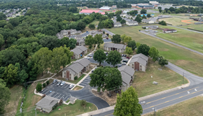 Russellville apartment for rent - A large building surrounded by trees and a parking lot.