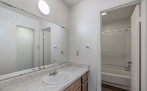 Russellville apartment for rent - A bathroom with a marble countertop and a round mirror.