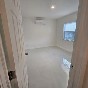Fort Lauderdale apartment for rent - A white door is open to a room with a window and a wall-mounted air conditioner.