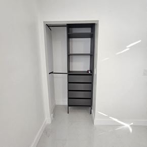 Fort Lauderdale apartment for rent - A tall black shelving unit with glass doors and drawers is in a white room.