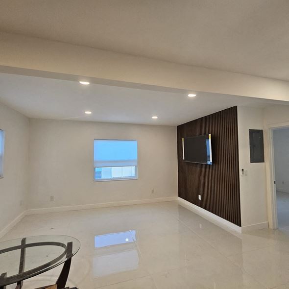 Fort Lauderdale apartment for rent - A modern living room with a glass table and a flat screen TV mounted on the wall.