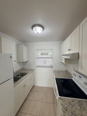 Fort Myers apartment for rent - A kitchen with white cabinets and a black stove top.