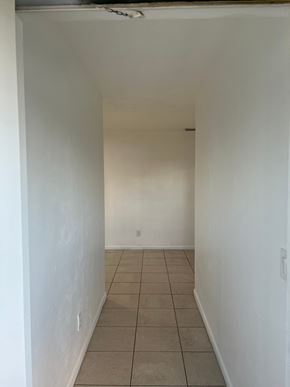 Fort Myers apartment for rent - A white hallway with tiled flooring and a white door at the end.
