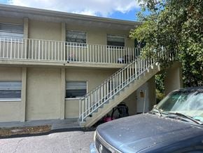 Fort Myers apartment for rent - A car is parked in front of a two-story building with a balcony.