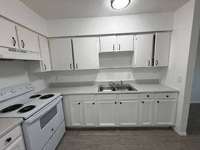 Fort Myers apartment for rent - A white kitchen with a stove, sink, and cabinets.