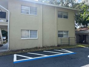 Fort Myers apartment for rent - A parking lot in front of a beige building with a white railing on the left.