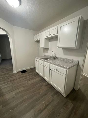 Lima apartment for rent - A kitchen with white cabinets and a granite countertop.