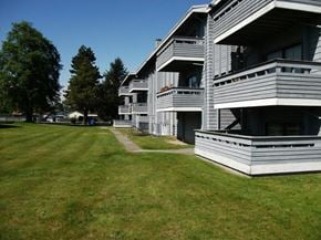 Surrey apartment for rent - A large grassy area in front of a building with a clear blue sky.
