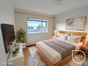 West Vancouver apartment for rent - A bedroom with a large bed, a flat screen TV, and a window overlooking a snowy landscape.