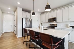 Castle Pines house for rent - a kitchen with white cabinets and a large island with chairs