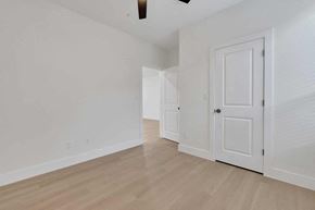 Houston apartment for rent - a bedroom with white walls and wood flooring and a white door