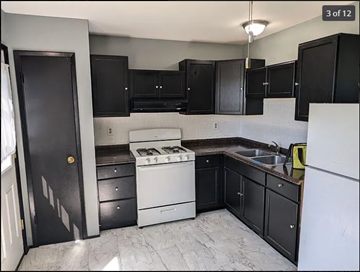 St. Louis house for rent - a kitchen with black cabinets and a white stove