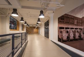 Cleveland apartment for rent - A long hallway with a rail on the left and a picture of cars on the right.