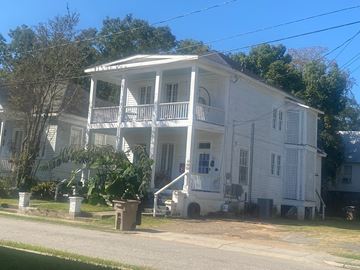Mobile house for rent - A white house with a porch and a tree in front.