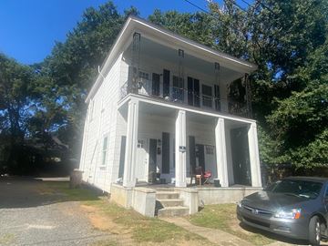 Mobile house for rent - A white house with a balcony and a car parked in front.