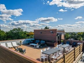 Cleveland apartment for rent - A rooftop patio with a table and chairs overlooking a building.