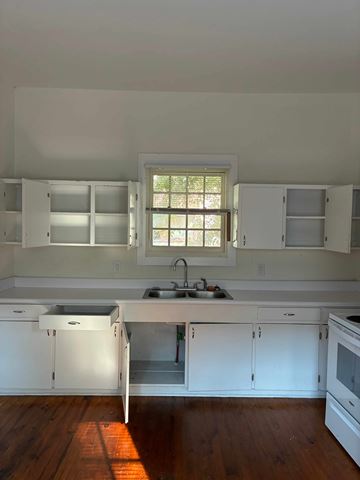 Mobile house for rent - A kitchen with white cabinets and a window.