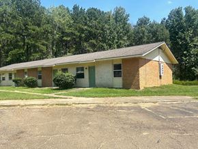 Gloster apartment for rent - a small brick house with a lawn and trees in the background