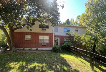 Louisville apartment for rent - the front of a brick house with a yard and a fence