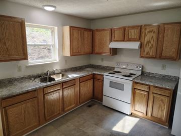 Grayson house for rent - a kitchen with wooden cabinets and a stove and a sink