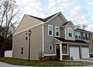 Charlotte house for rent - a house with brown siding and white garage doors