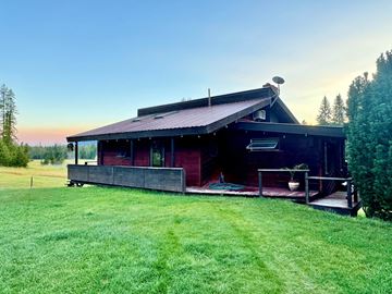 Whitefish house for rent - A house with a red roof and a porch is surrounded by a grassy lawn.