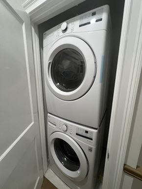 Brighton apartment for rent - A white washing machine is in a small space.