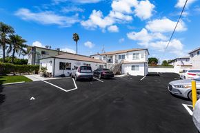 North Hollywood apartment for rent - A parking lot with cars parked and a white building in the background.