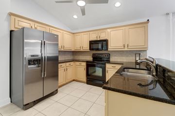 Fort Myers house for rent - A kitchen with a black counter top and a stainless steel refrigerator.