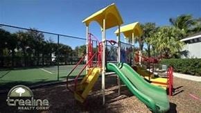 Fort Myers house for rent - A playground with a yellow and green slide and a red swing set.