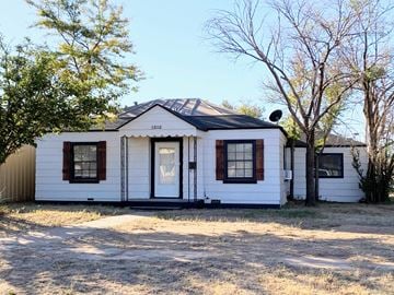 Levelland house for rent - A white house with a black roof and a brown door.