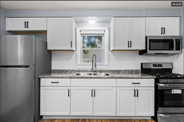 Ferguson house for rent - a kitchen with white cabinets and a sink and a refrigerator