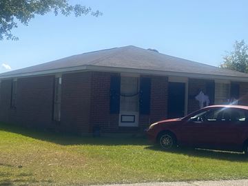 Mobile house for rent - A red car is parked in front of a brick house.