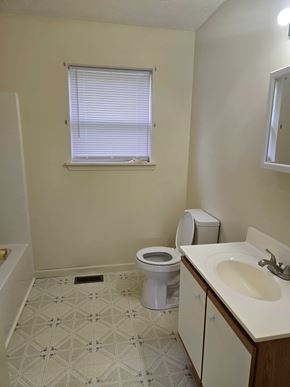 West Liberty house for rent - A bathroom with a toilet, sink, and a window with blinds.