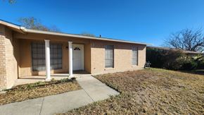 Killeen house for rent - a small tan brick home with a sidewalk and a white door