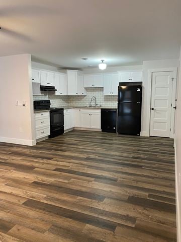 Kentville apartment for rent - a kitchen with white cabinets and black appliances and a wooden floor