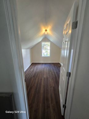 St. Louis house for rent - the view from the hallway of a renovated attic room with wood floors and a window