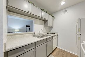 Austin apartment for rent - A kitchen with a white counter top and grey cabinets.