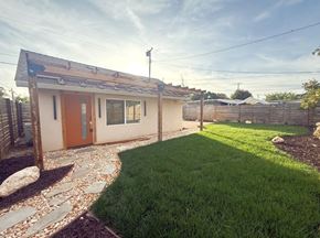 Merced house for rent - a small white house with a grass yard and a door