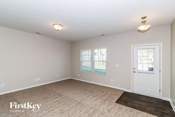 Troutman house for rent - a spacious living room with carpet and a white door
