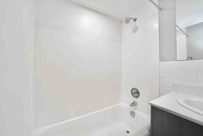 Winnipeg apartment for rent - A white bathroom with a tub, sink, and mirror.